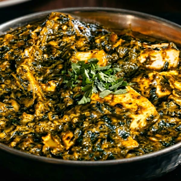 Palak Paneer, a vibrant green spinach and cheese curry, served in a hammered metal bowl.